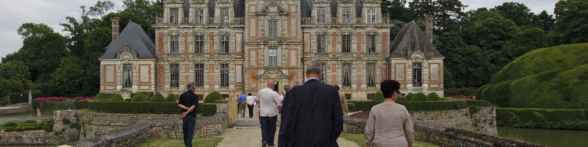 A grand château with a symmetrical facade, multiple chimneys, and a central dome.