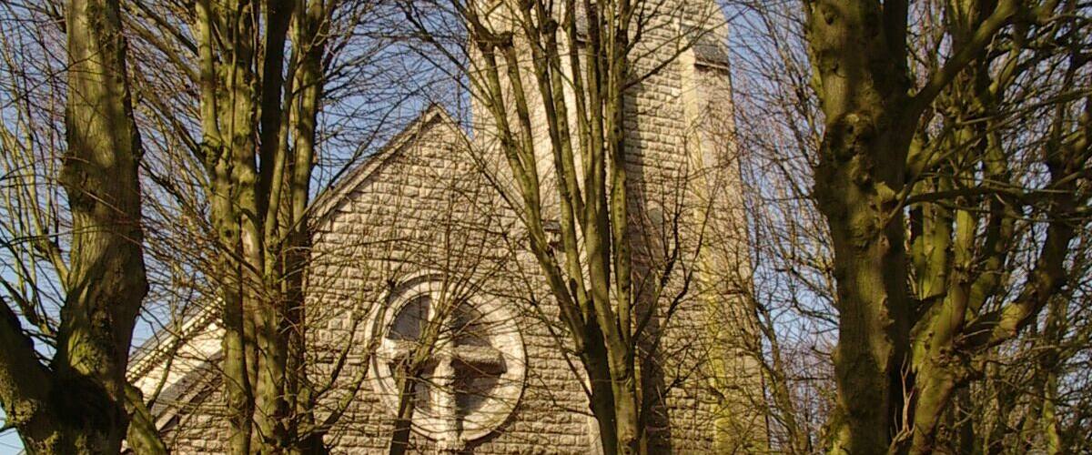 A historic stone church with a large arched entrance and a clock tower.