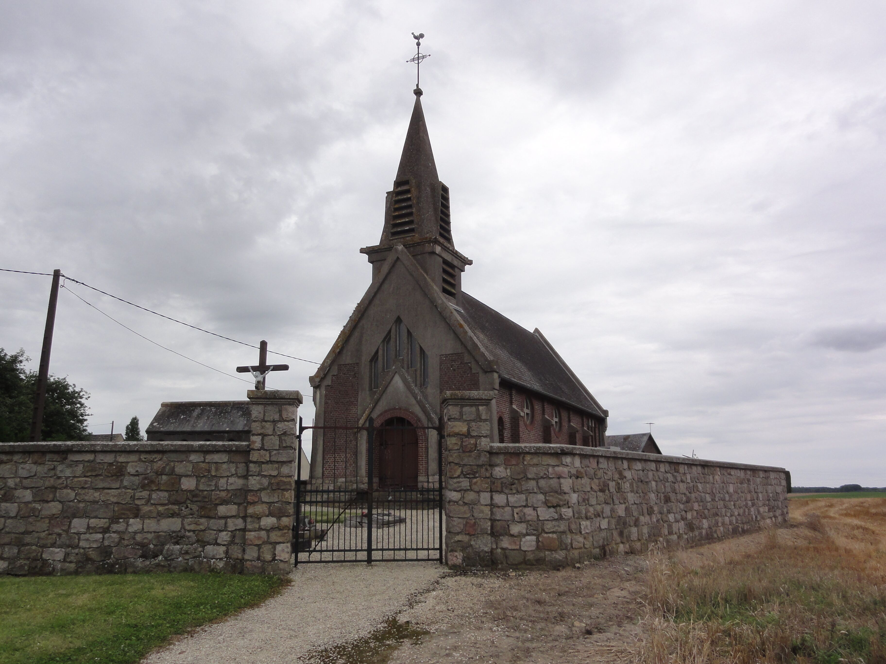 A church with a stone wall and a metal gate.