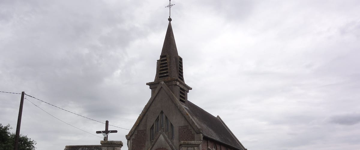 A church with a stone wall and a metal gate.