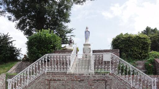 Una estatua sobre una escalera de ladrillo con barandillas blancas ornamentadas.