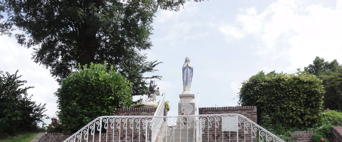 A statue on a brick staircase with ornate white railings.
