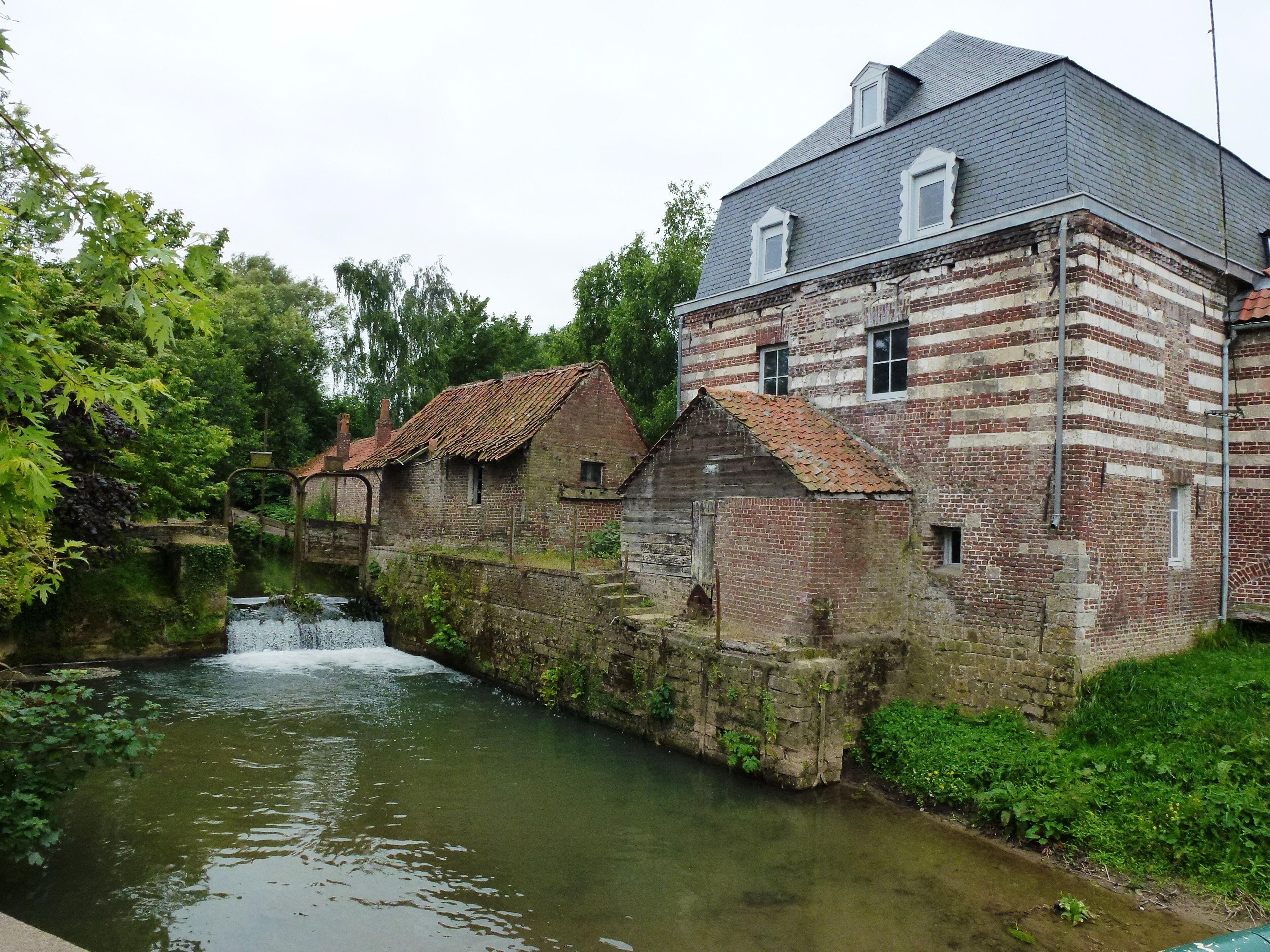A historic brick building with a water channel and a small waterfall.