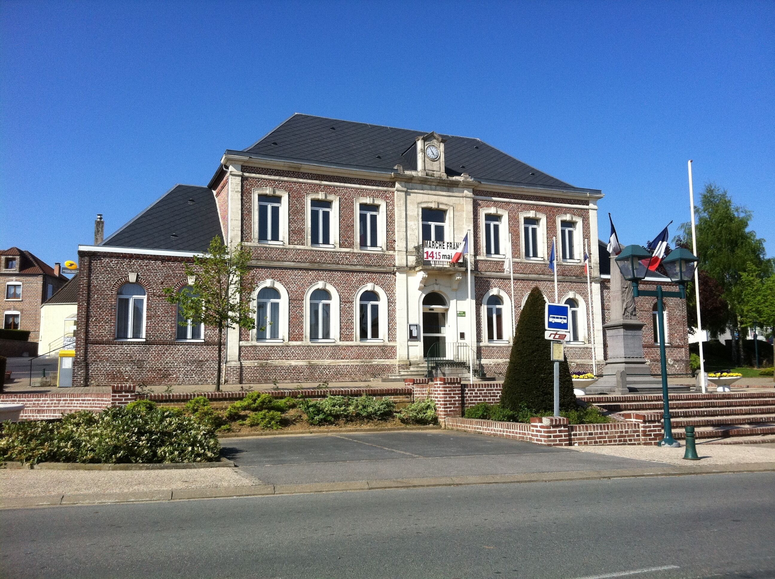 A historic building with a clock tower, a statue, and flags.