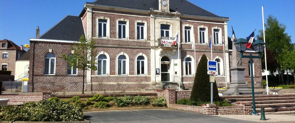 A historic building with a clock tower, a statue, and flags.