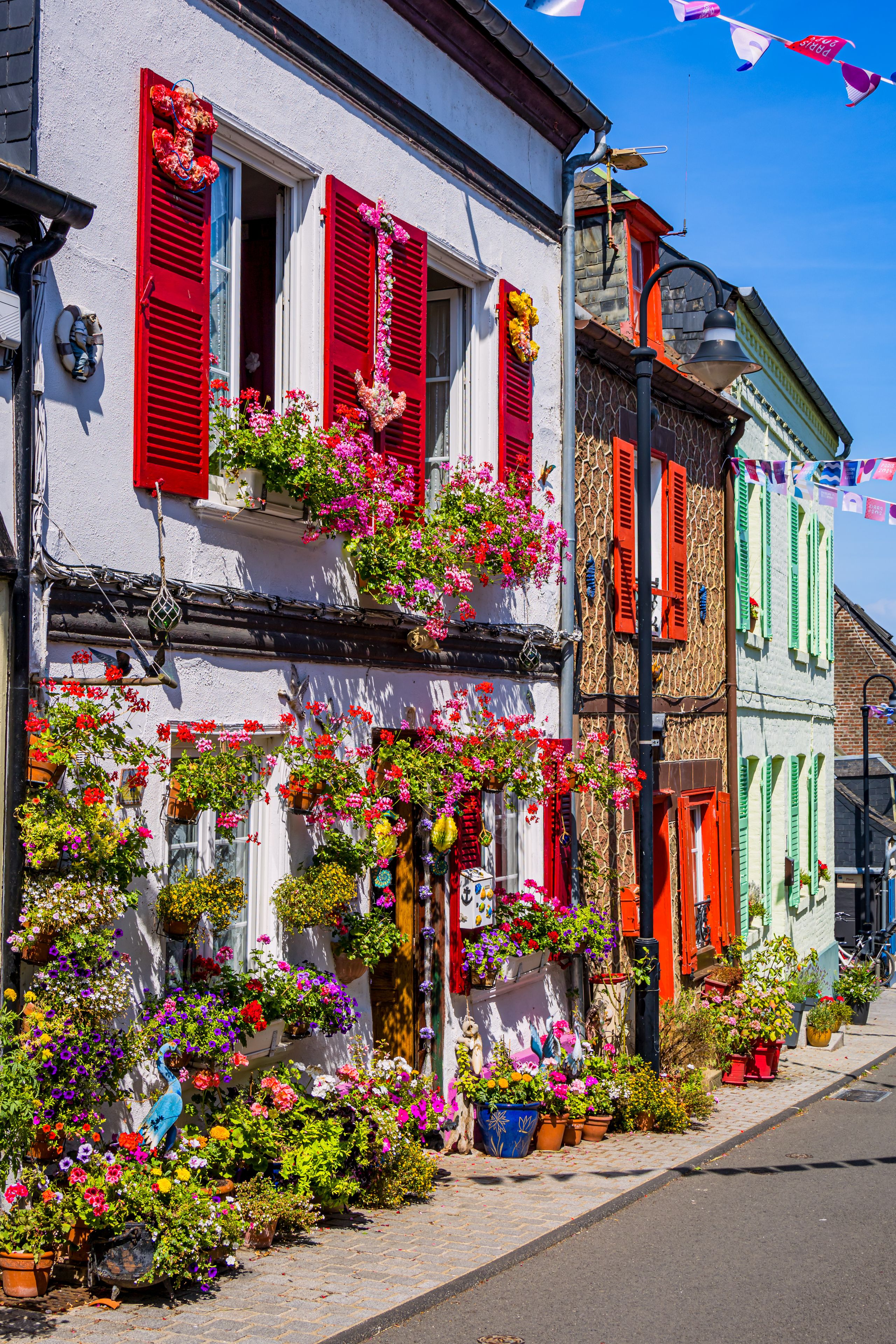 A colorful street with buildings adorned with red shutters and vibrant flowers.