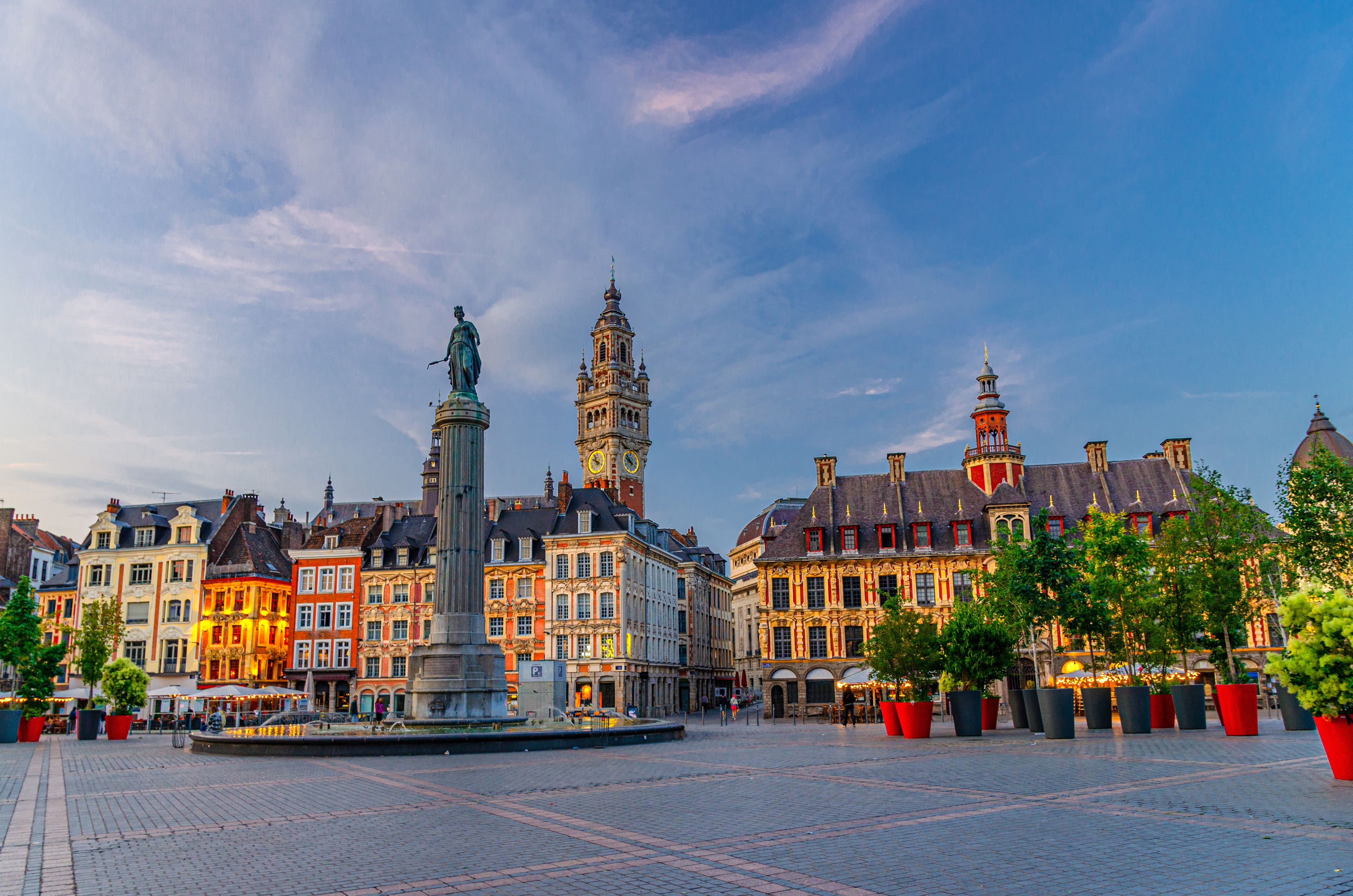 Een historisch plein met een centraal monument, versierde gebouwen en een klokkentoren.