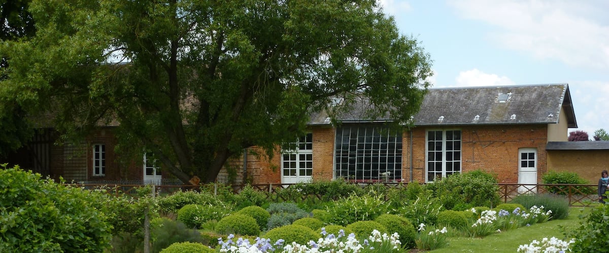 A garden with a lawn, white and blue flowers, and a brick building.
