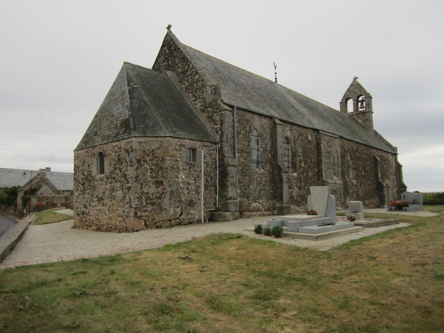 Una iglesia de piedra con un campanario y un cementerio frente a ella.
