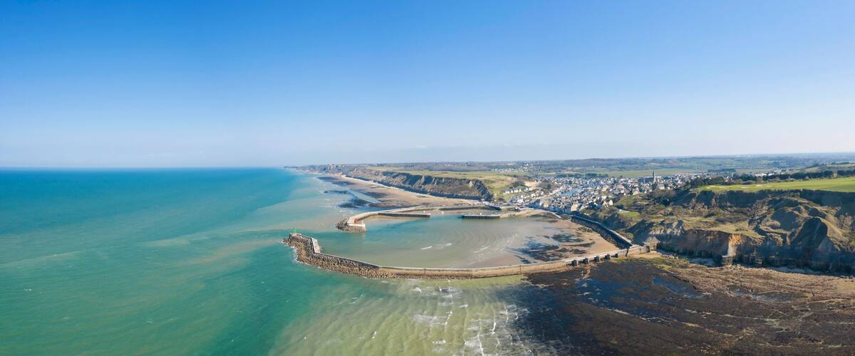 A coastal town with a beach, cliffs, and a lighthouse.