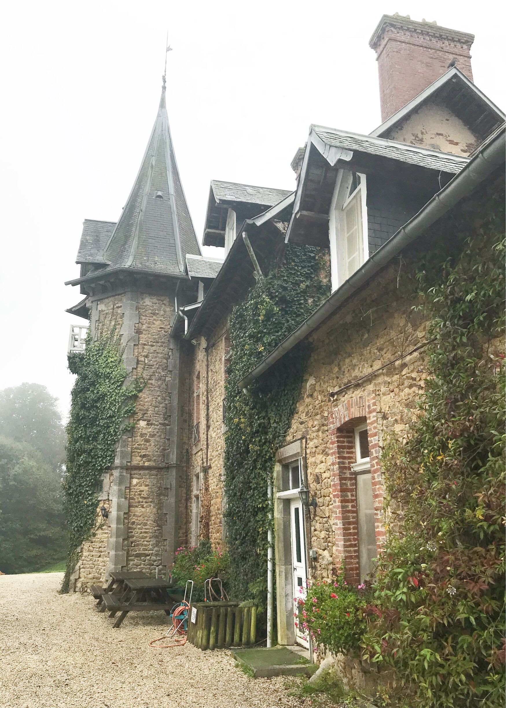 A historic stone building with ivy-covered walls and a steeply pitched roof.