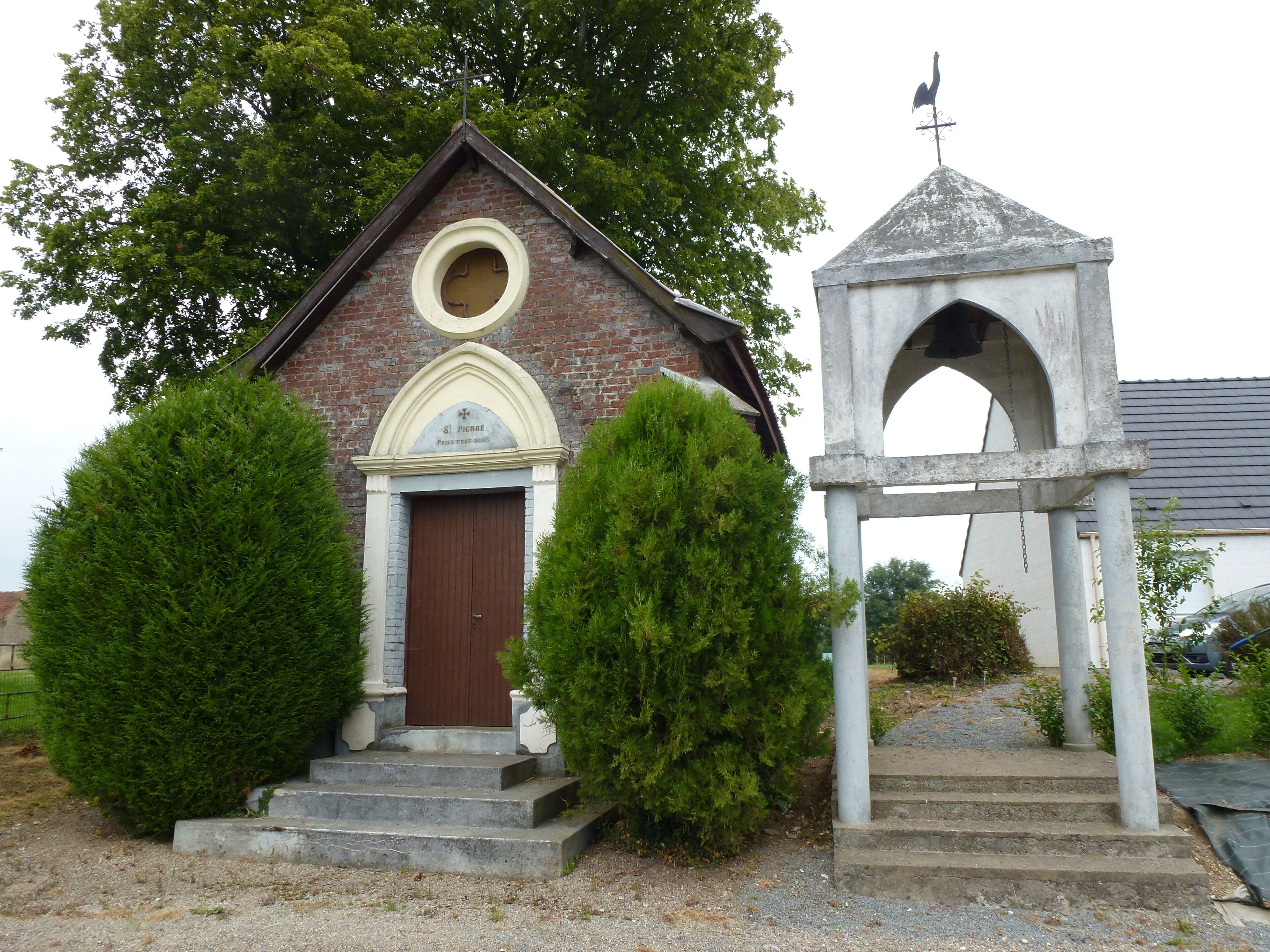 A small brick church with a brown door and a bell tower.