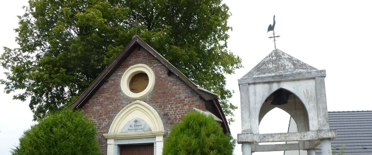 A small brick church with a brown door and a bell tower.