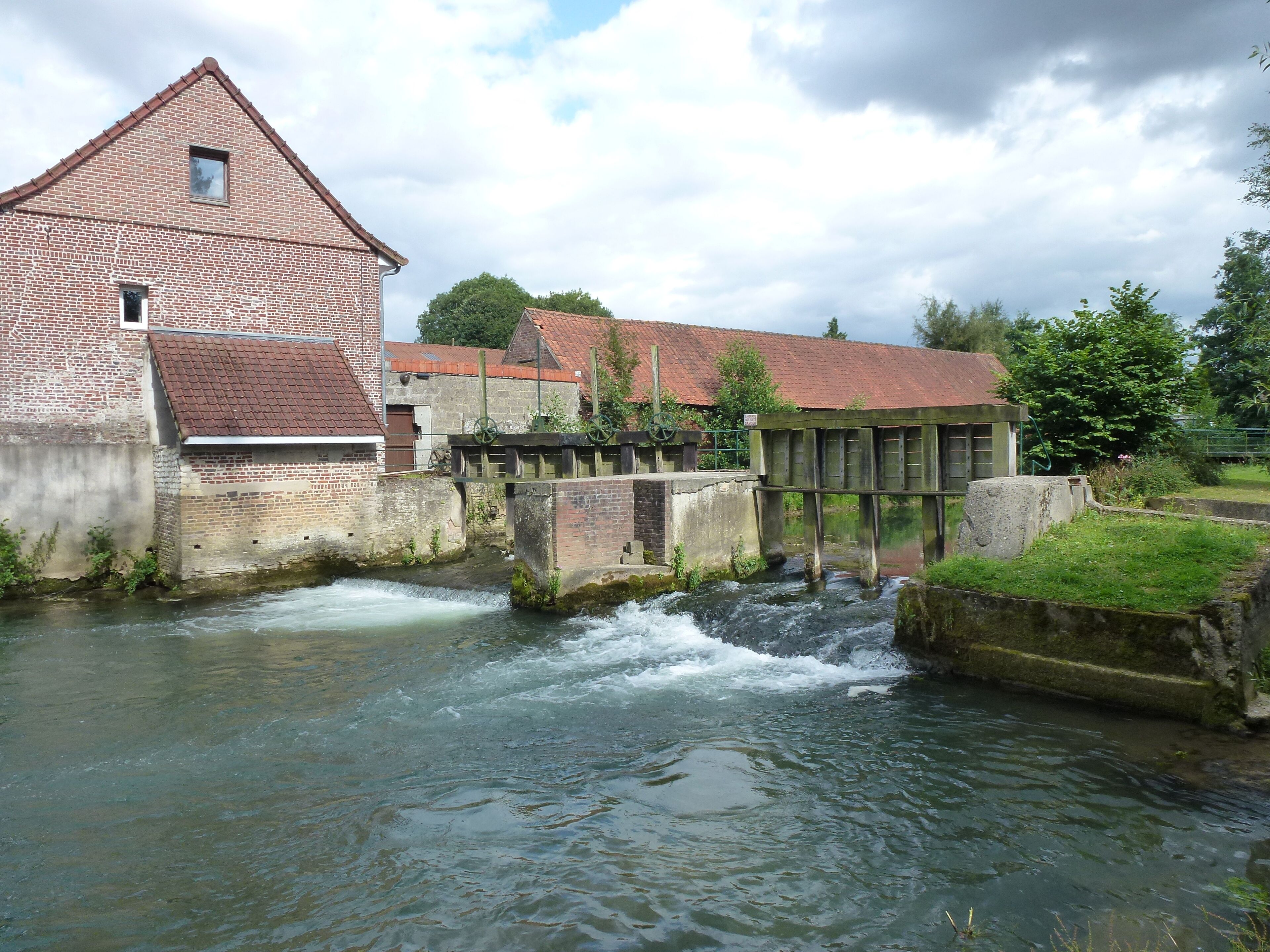 A brick mill with a water wheel and a lock system in a river.