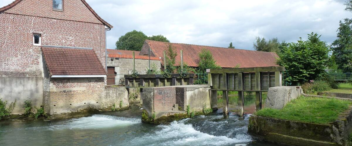 A brick mill with a water wheel and a lock system in a river.
