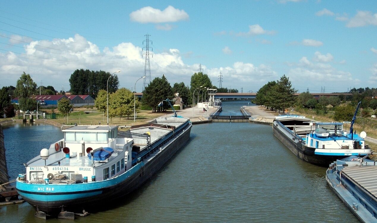A canal with two boats docked at a lock.