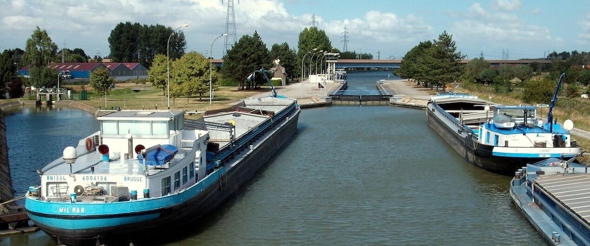 A canal with two boats docked at a lock.