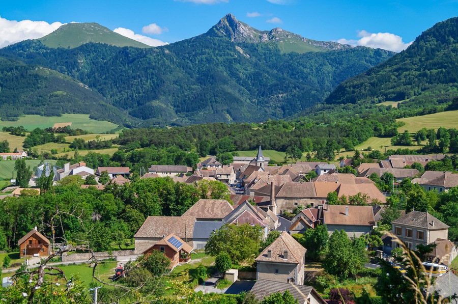 Ein Dorf eingebettet in ein Tal, mit einem markanten Berg im Hintergrund.