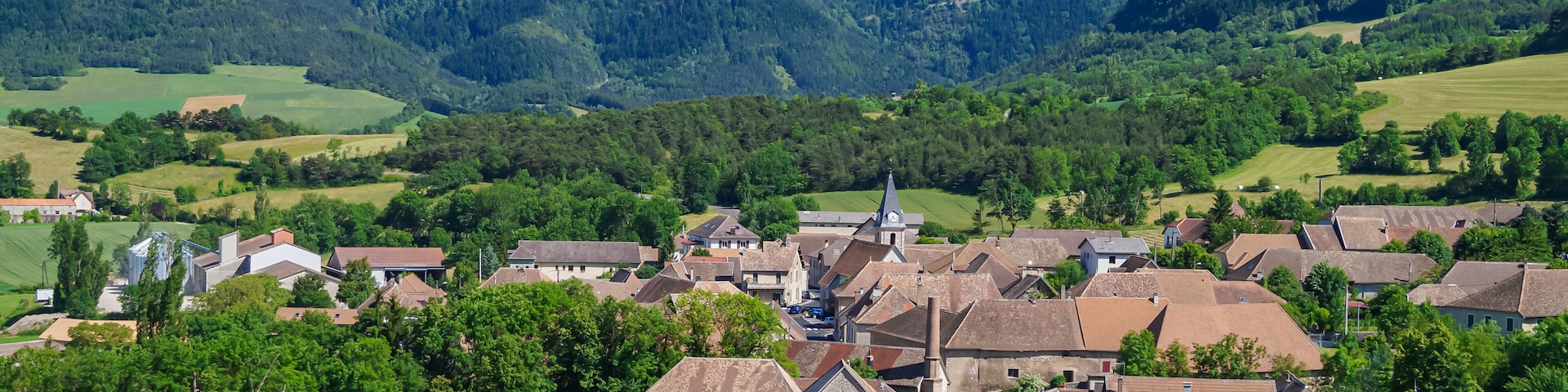 Un village niché dans une vallée, avec une montagne imposante en toile de fond.