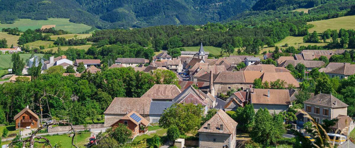 A village nestled in a valley with a prominent mountain in the background.
