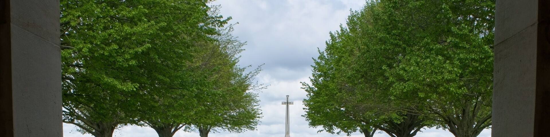 A memorial with a white monument surrounded by green grass and trees.