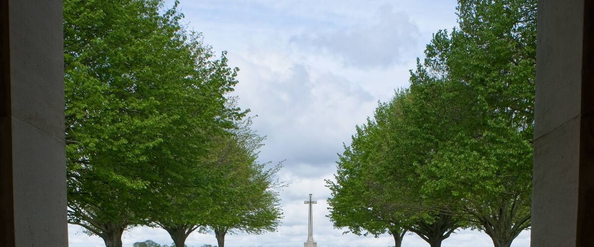 A memorial with a white monument surrounded by green grass and trees.