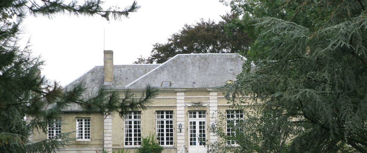 A large, historic building with a stone facade, multiple windows, and a prominent staircase leading to the entrance.