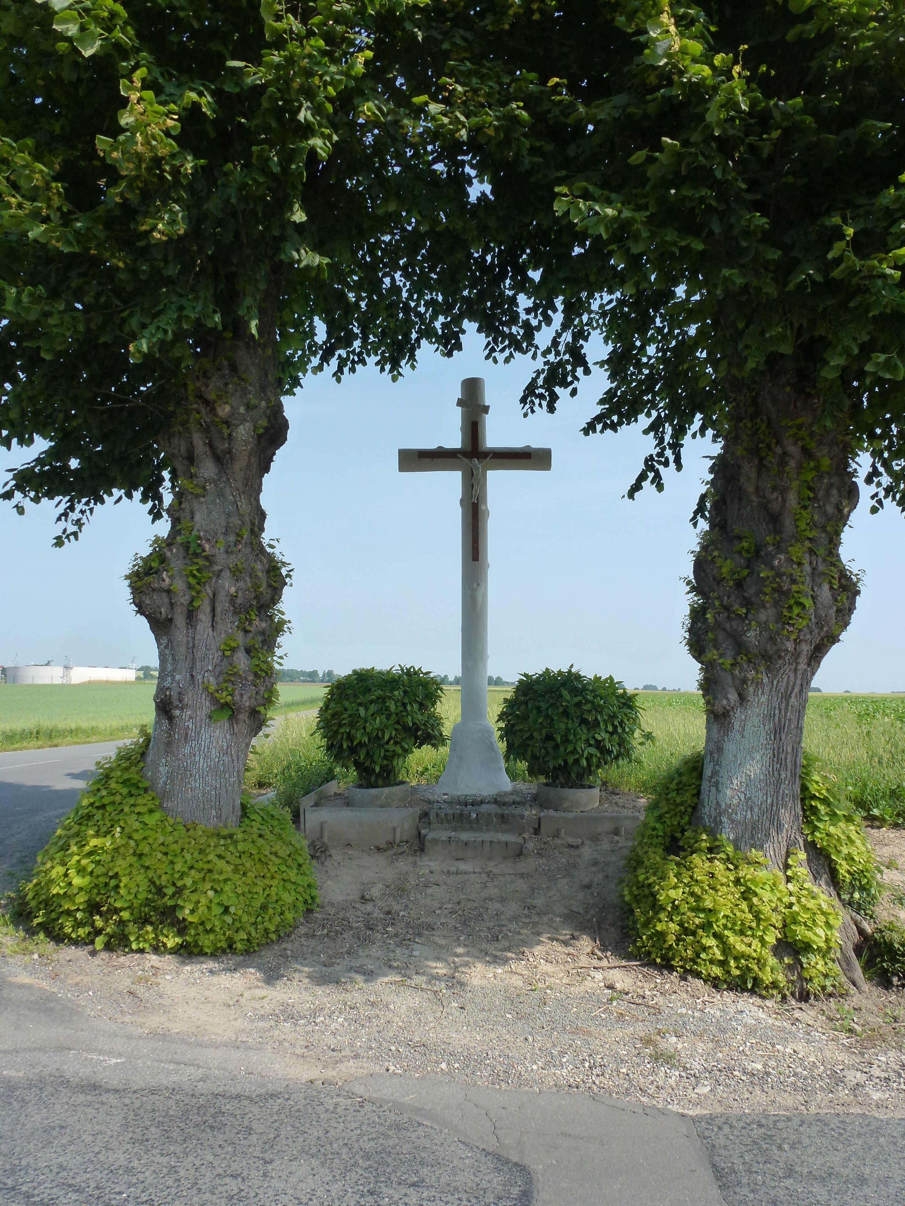 A cross monument surrounded by trees and bushes.
