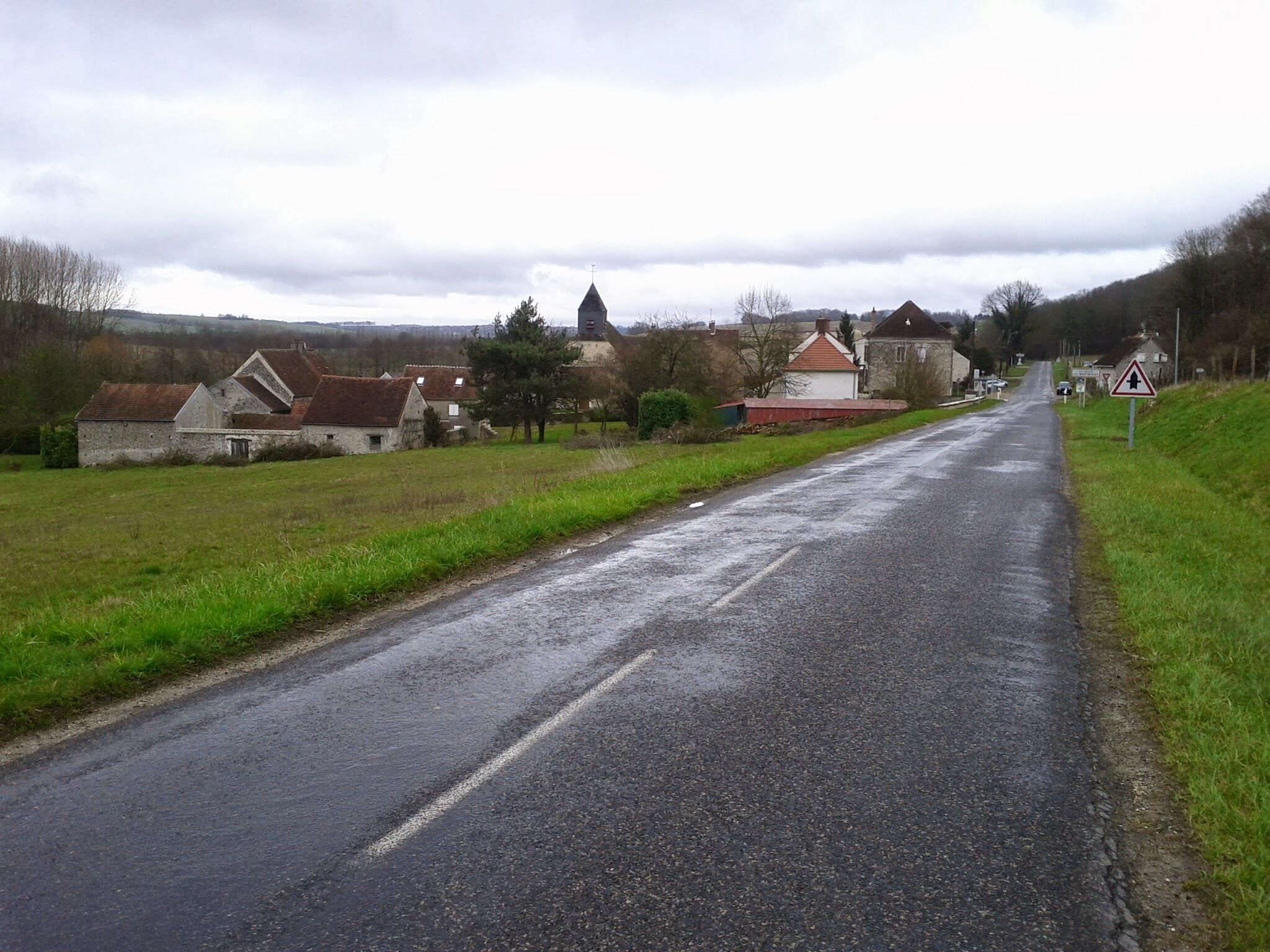 A rural road with houses and a church in the distance.