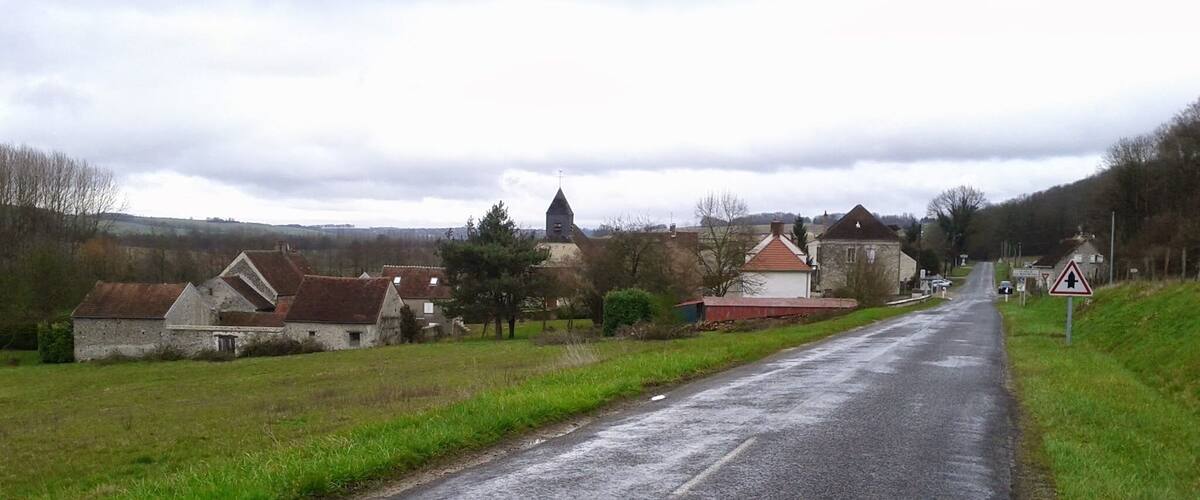 A rural road with houses and a church in the distance.