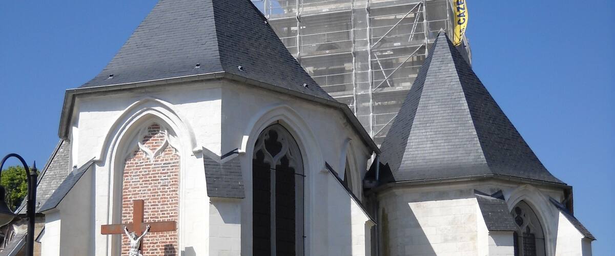 A church with a cross, a steeple, and scaffolding.