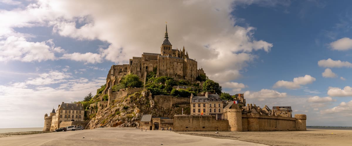 A historic castle on a hill overlooking a beach.