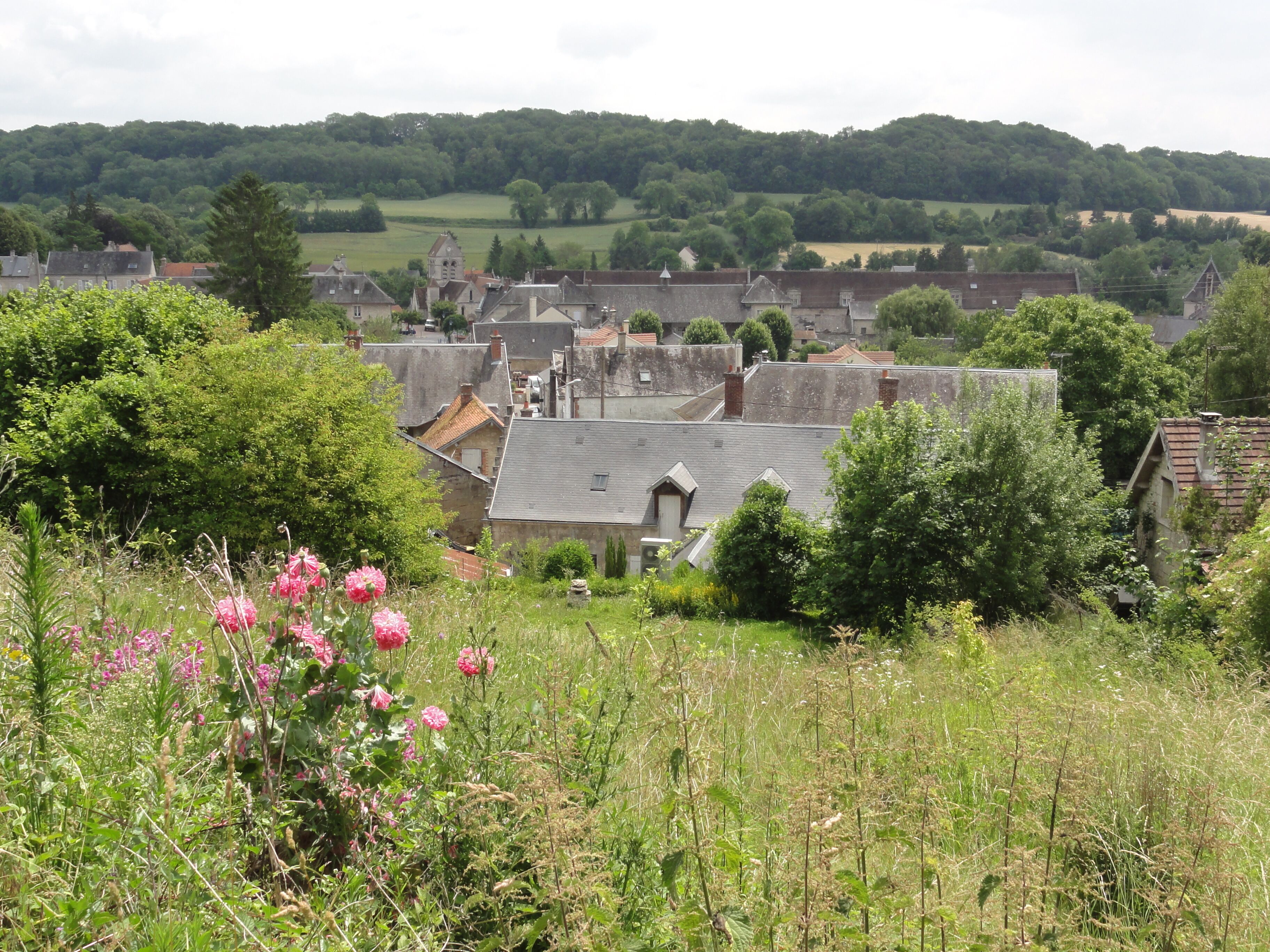 A rural village with stone houses, a church, and rolling hills in the background.