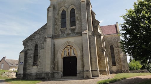 Una iglesia antigua con un campanario alto, ventanas arqueadas y una puerta negra.