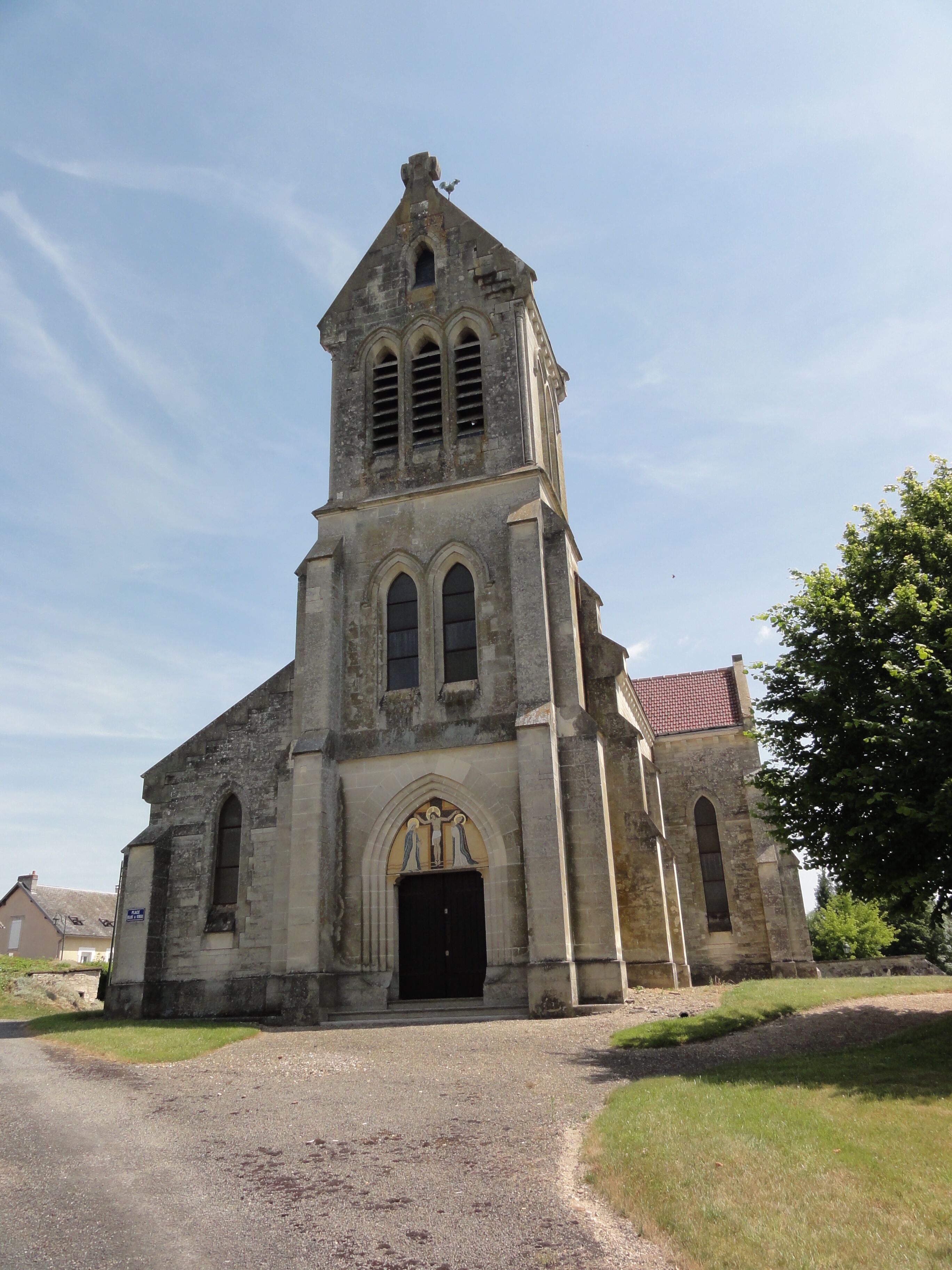 An old church with a tall bell tower, arched windows, and a black door.