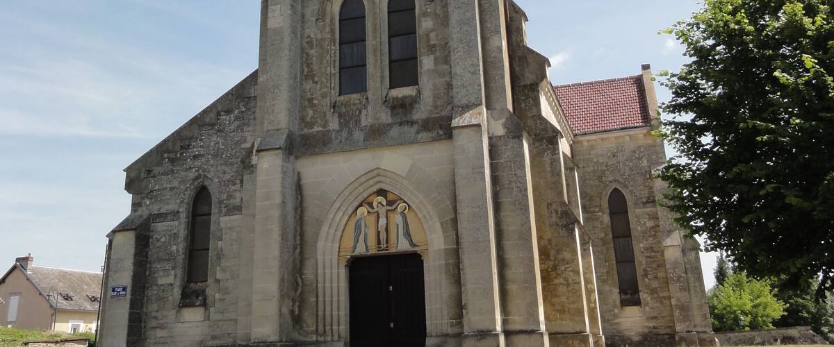 An old church with a tall bell tower, arched windows, and a black door.