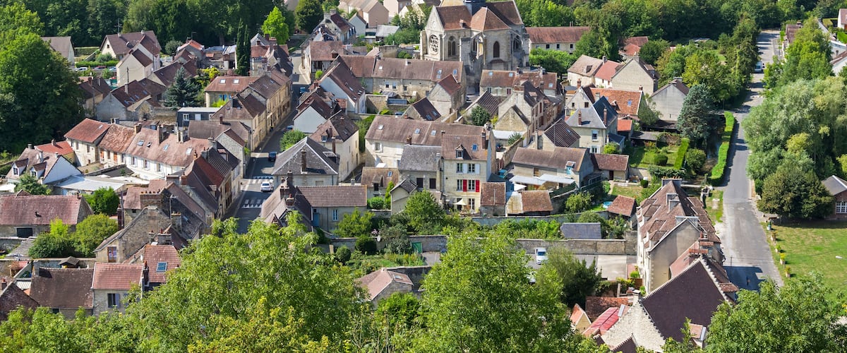 A historic town with a prominent church, surrounded by lush greenery and rolling hills.