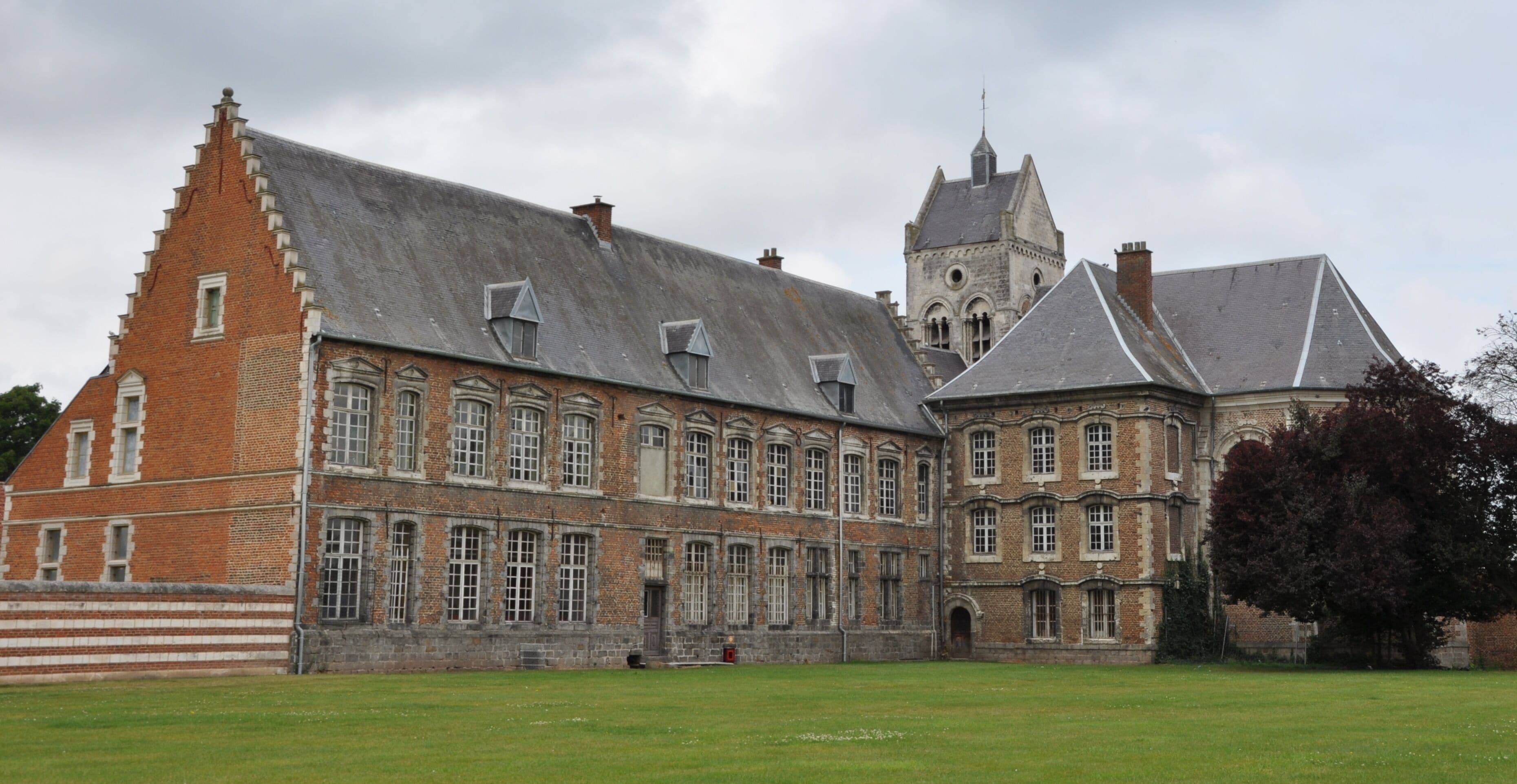 A large, historic building with a prominent tower and a courtyard.