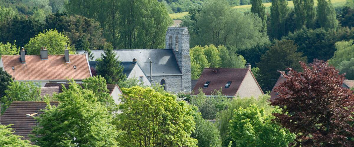 A rural landscape with rolling hills, a stone church, and residential houses.