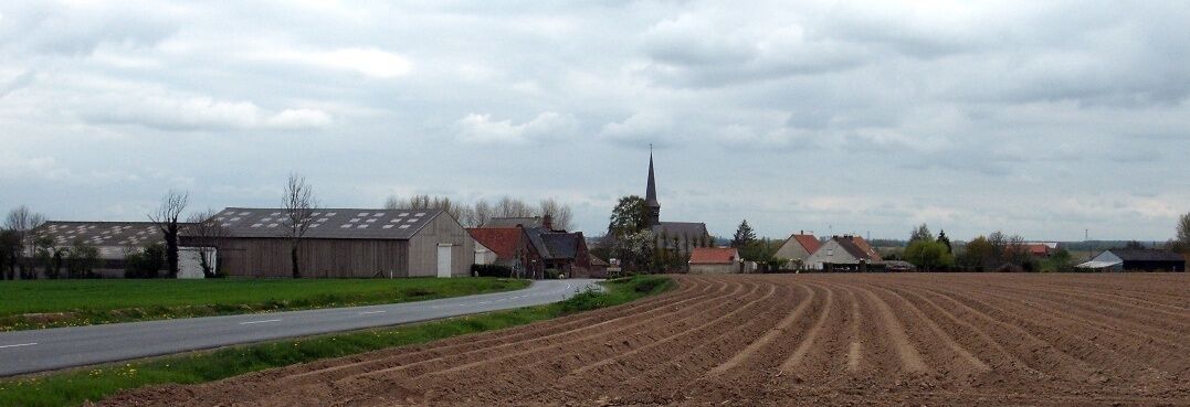 A rural landscape with a road curving through fields, a church with a steeple, and several farm buildings.