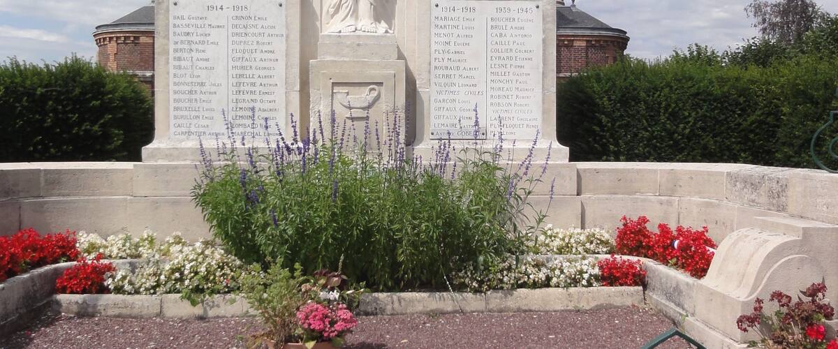A memorial with a statue, inscriptions, and flower beds.