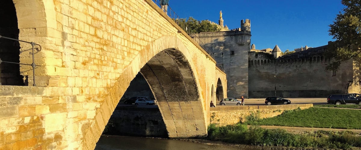 A stone bridge over a river with a castle in the background.