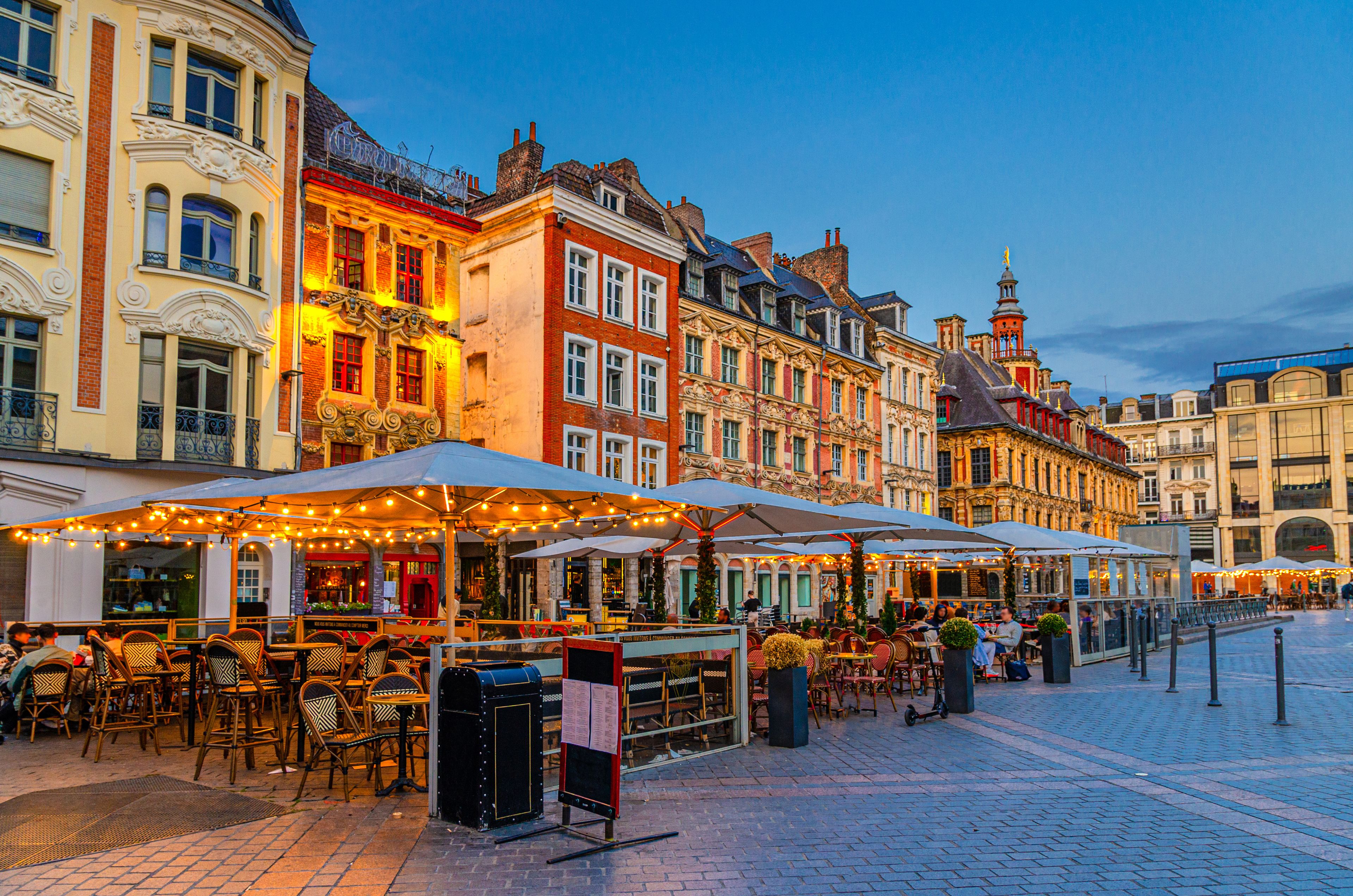A historic European street lined with colorful buildings and outdoor cafes.