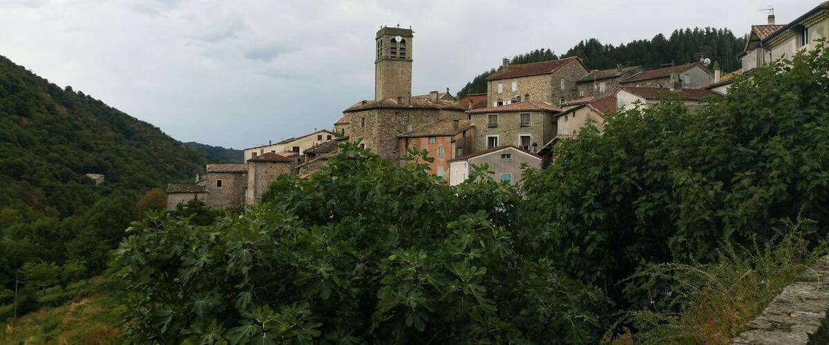 A village with stone buildings, a prominent tower, and lush greenery.