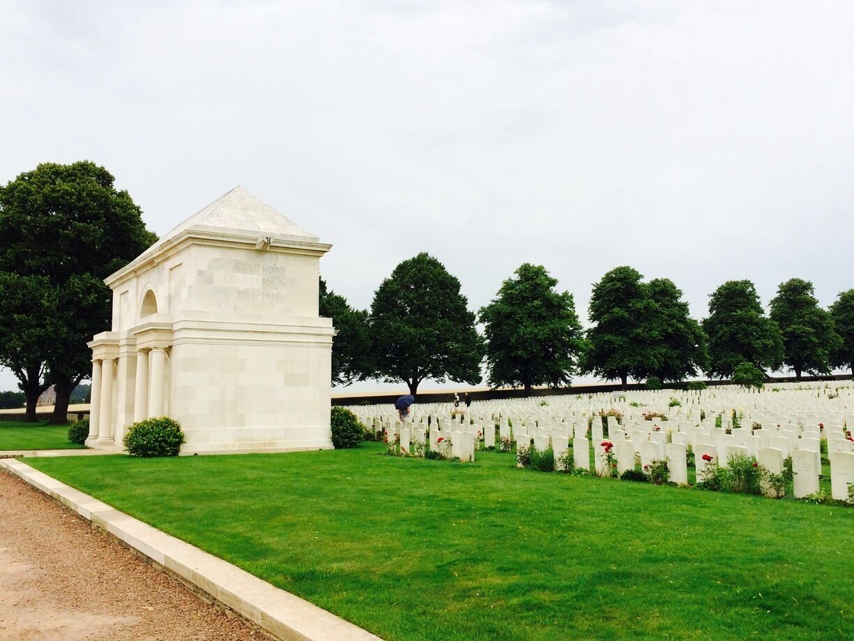 A cemetery with a white monument and rows of white headstones.