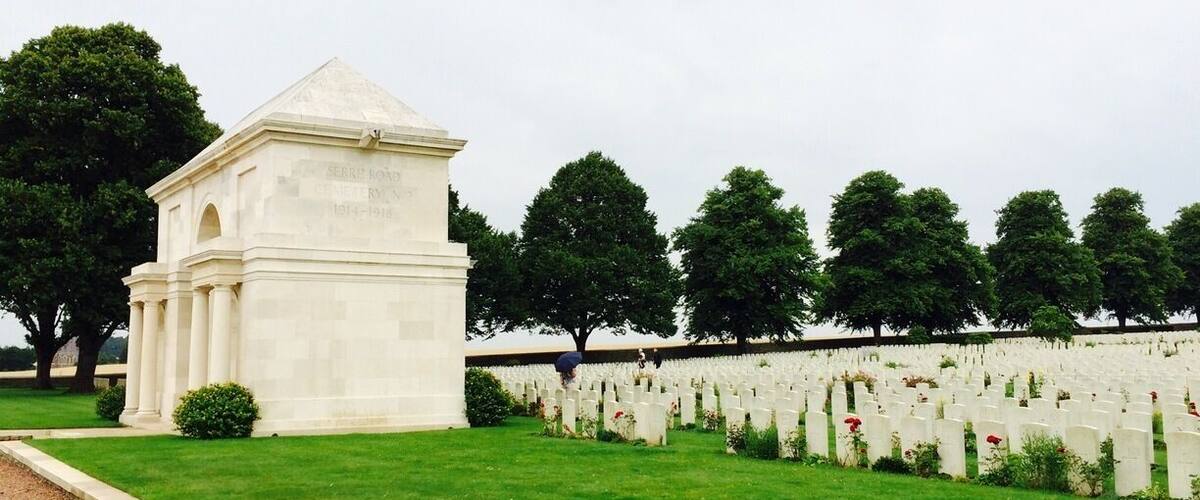 A cemetery with a white monument and rows of white headstones.