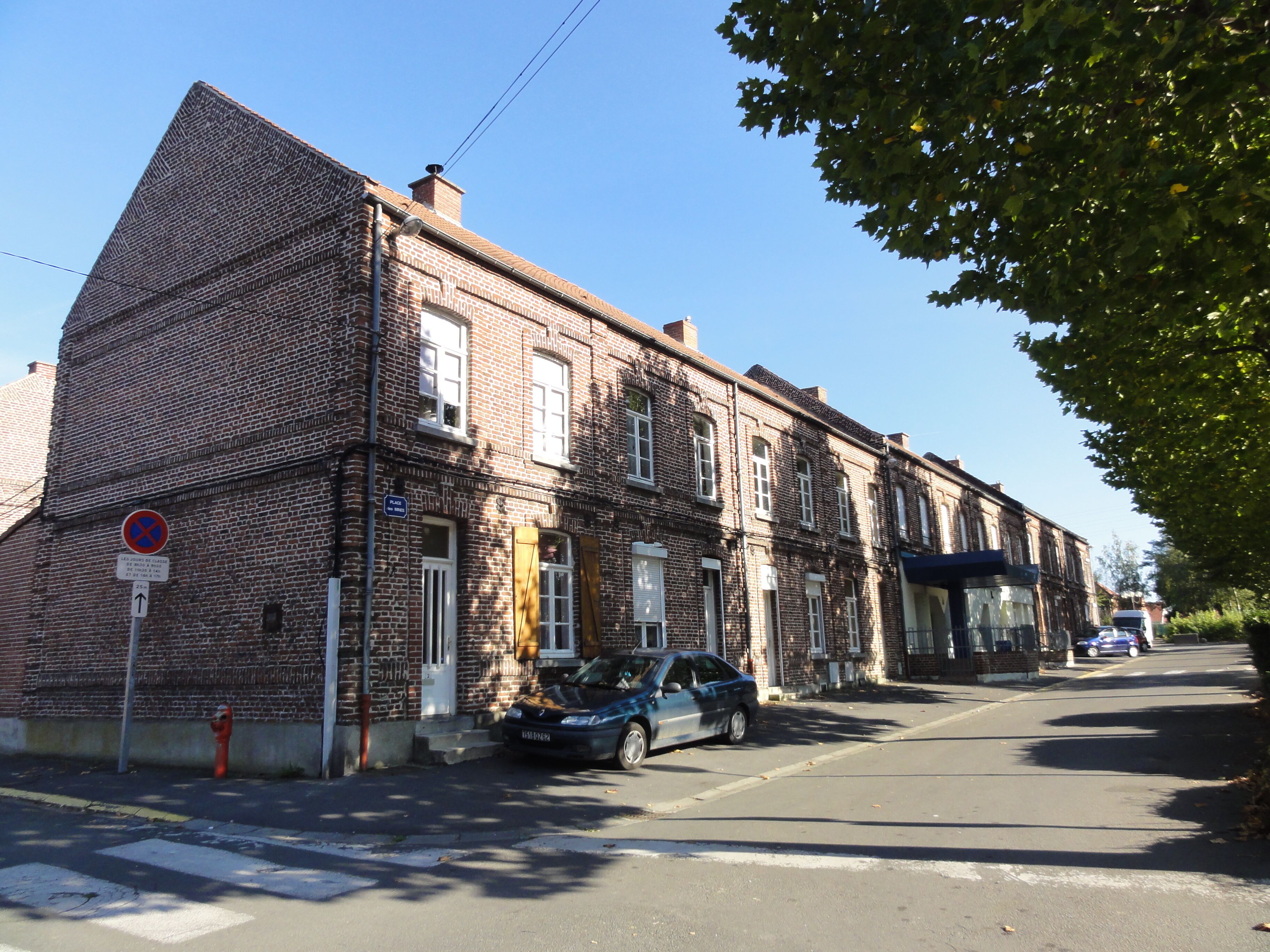 A brick building with a blue car parked in front.