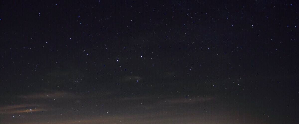 A starry night sky over a hilly landscape.