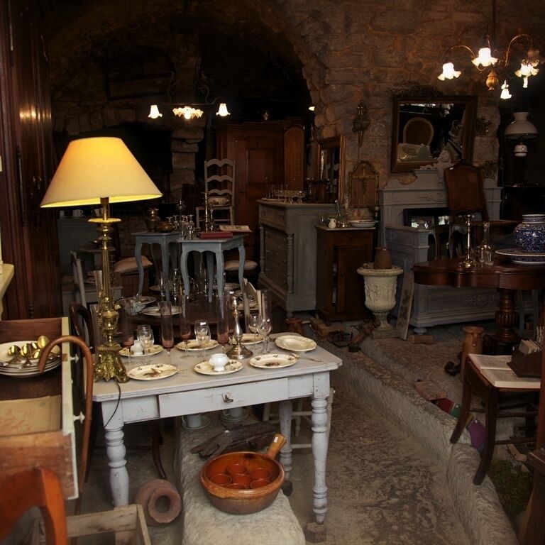 A cluttered antique shop with various items on tables and shelves.