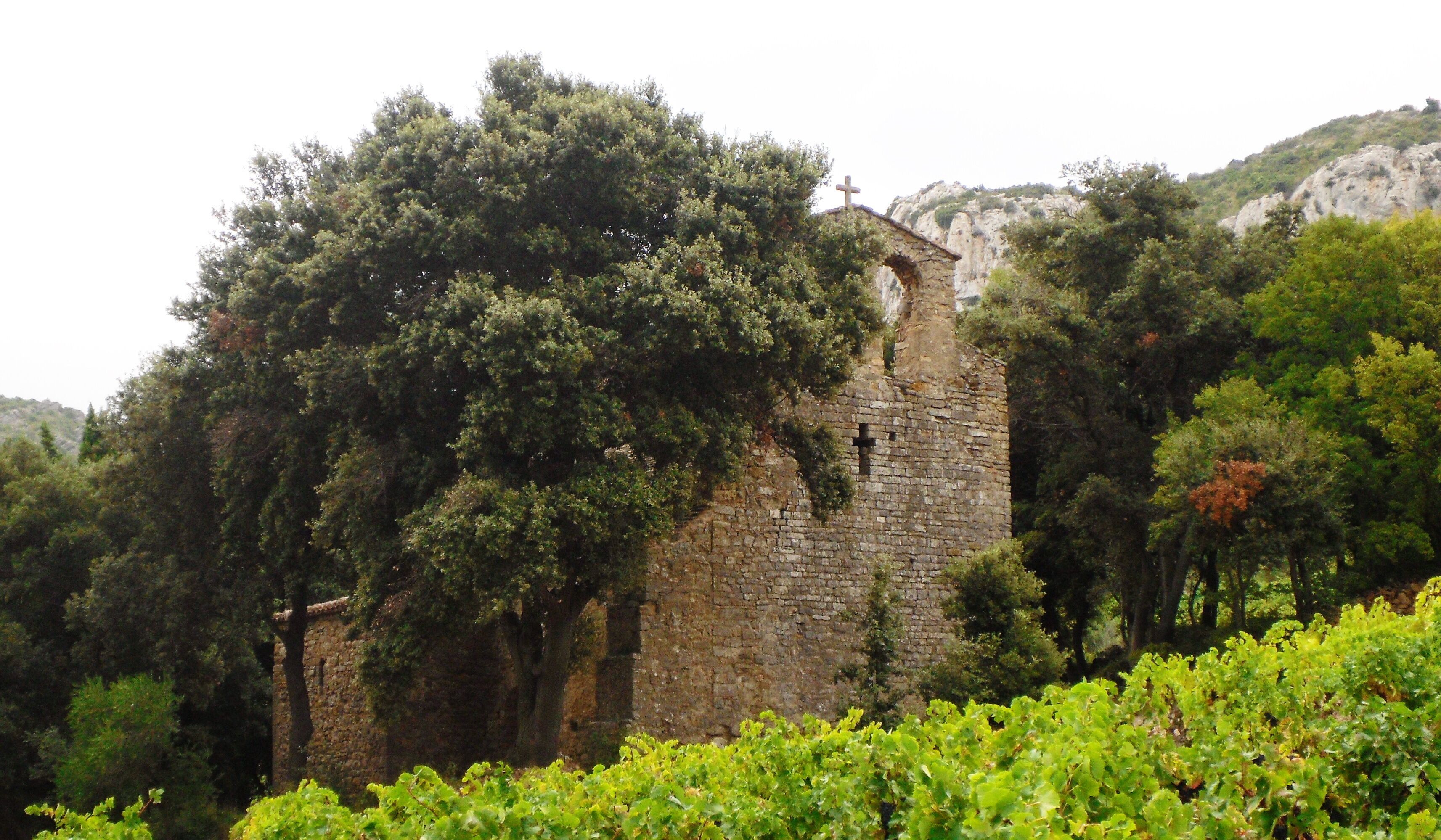 A stone tower surrounded by lush greenery and a cross on top.